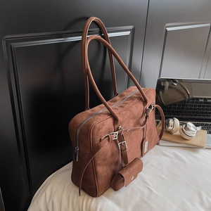 Brown suede tote bag with metal buckles and small pouch in a modern office setup