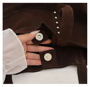Close-up of magnetic buckle closure and silver rivet details on brown suede tote bag