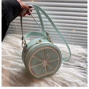 Close-up of mint green lemon shaped bag with golden zipper and luxury sewing detail