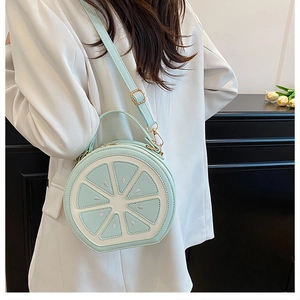 Close-up of mint green lemon-shaped crossbody bag with a white suit and tulip background