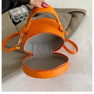 Detailed interior of bright orange round mini PU leather crossbody bag with gold zipper