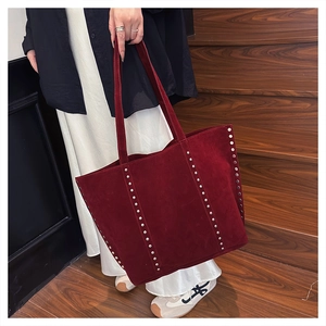 Detail of burgundy suede tote bag featuring silver rivets and large capacity interior