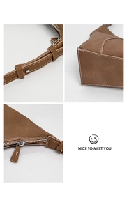 Detail showing litchi texture brown leather with silver metal buckle and sturdy stitching