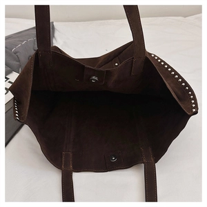 Macro shot of dark brown suede tote bag featuring silver studs and magnetic closure
