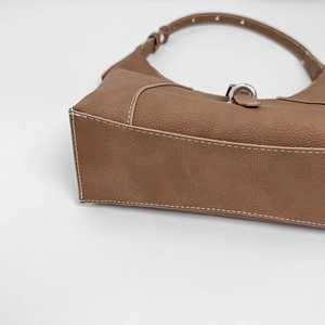 Detail view of brown lychee leather underarm bag with white stitching and silver hardware