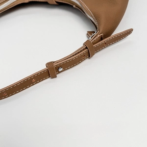 Detail of brown lychee grain leather strap with white contrast stitching and silver buckle