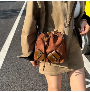 Detailed view of brown suede bucket bag with drawstring closure and vintage metal hardware