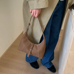 Detail of brown lychee leather shoulder bag with white contrast stitching and buckle strap