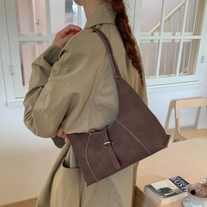 Detail of dark brown suede shoulder bag with contrast white stitching and silver hardware