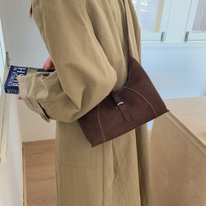 Detail of dark brown suede underarm bag with contrast stitching and buckle closure