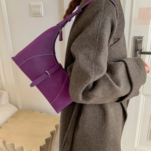 Detail of purple leather underarm bag featuring contrast stitching and silver metal buckle