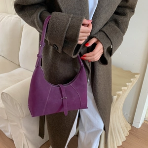Detail of purple matte leather underarm bag with white stitching and metal buckle
