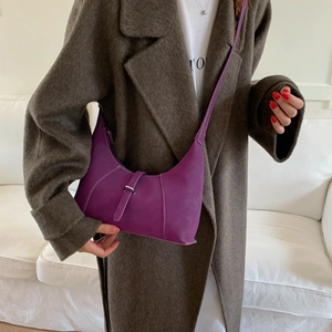 Detail of purple crescent underarm bag with contrast stitching and metal buckle accent