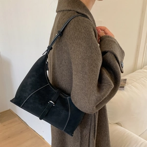 Close-up of black suede hobo bag with white contrast stitching and metal buckle detail
