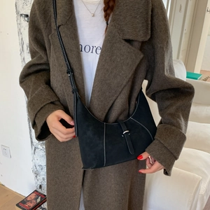 Detailed view of a black half-moon bag with white contrast stitching on a model
