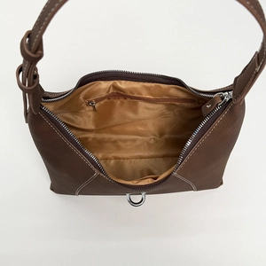 Detail view of the brown lychee leather handbag interior with smooth satin lining
