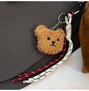 Detail of plush bear charm with woven climbing ropes and silver metal keyring accessory