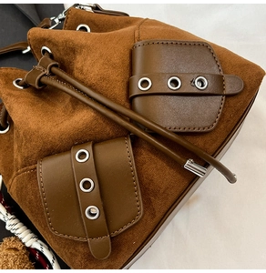Detailed macro view of brown faux suede bucket bag with silver metal eyelet accents