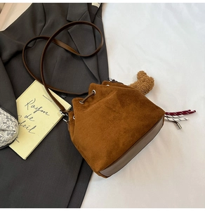 Detail of brown faux suede bucket bag with leather strap and plush bear charm