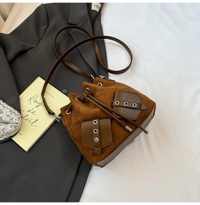 Detail of a brown faux suede bucket bag with flap pockets on a grey suit jacket