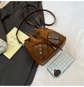 Top-down view of brown faux suede bucket bag with drawstring and silver grommet details