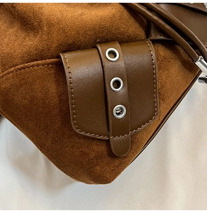 Detailed close-up of brown suede bucket bag with leather strap and silver eyelets