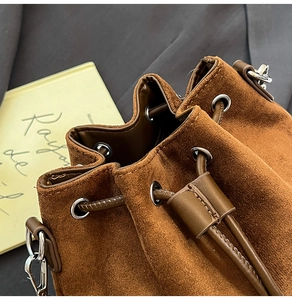 Detailed view of the drawstring closure and premium suede texture on dark brown bucket bag