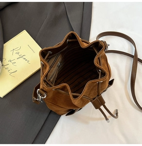 Interior view of brown faux suede bucket bag with striped lining and zipper pocket