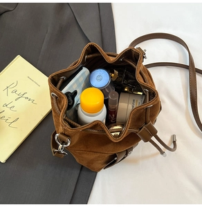Detail view of brown suede bucket bag interior with drawstring and daily essentials