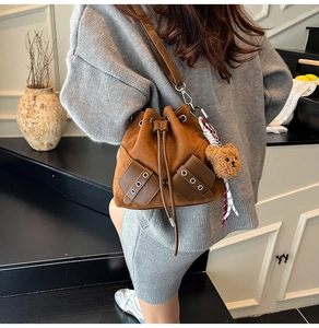 Detail of vintage brown suede bucket bag featuring drawstring closure and bear charm