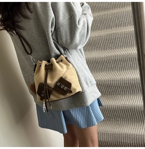 Detail of drawstring bucket bag featuring retro suede texture and dual utility pockets