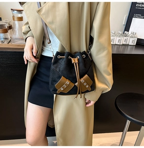 Close-up of retro black faux suede bucket bag featuring brown leather drawstring detail