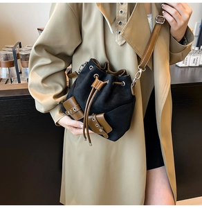 Detail of vintage drawstring bucket bag featuring brown leather straps and black suede texture