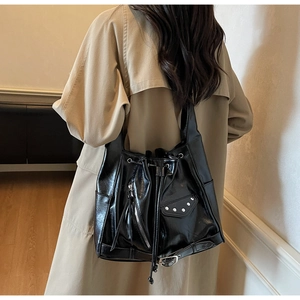 Detail of black glossy bucket bag with motorcycle style zippers and studs on shoulder