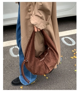 Sac à bandoulière en daim marron foncé porté avec un trench-coat en mode street style