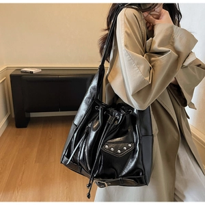 Detail of high-gloss leather bucket bag with silver studs and zipper accents