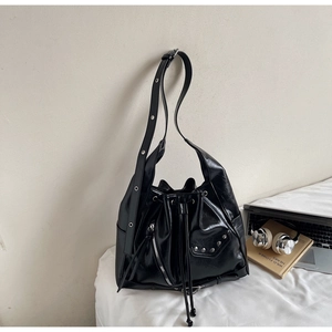 Detailed shot of black bucket bag with silver studs, glossy leather, and drawstring detail