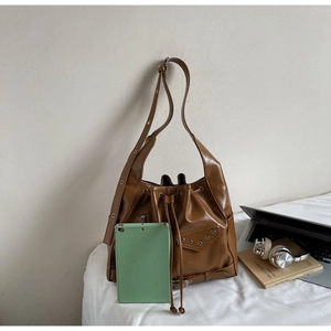 Detailed view of brown bucket bag showing large capacity with a green tablet inside