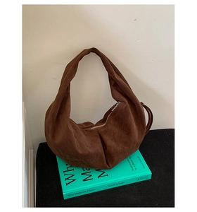 Détail du sac hobo en daim marron foncé avec bandoulière nouée et fermeture éclair argentée