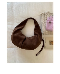 Vue à plat d'un sac hobo en daim marron avec cordon de serrage sur lin blanc