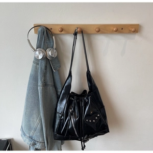 Detail of vintage black bucket bag with silver studs and tassels on a wooden hanger