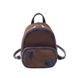 Dettaglio mini zaino vintage con toppe a stella e bordo a quadri su materiale scamosciato