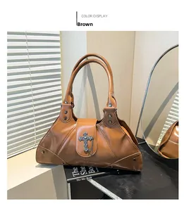 Detail of a brown glossy leather punk tote bag with silver cross charm and metal chain
