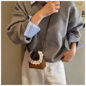 Detail of a brown mini crossbody bag featuring white lace trim handle on a model
