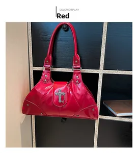 Detail of red patent leather punk handbag featuring silver cross charm and metal studs