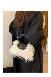 Detail of plush faux fur handbag with black leather flap and handle shown on a model