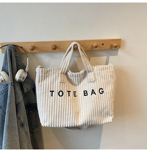 Detail of corduroy tote bag with TOTE BAG embroidery hanging on a wooden hook