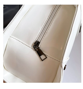 Detail of white glossy leather bag with black metallic zipper and precision stitching
