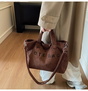 Detail of dark brown corduroy tote bag showing striped texture and black logo lettering