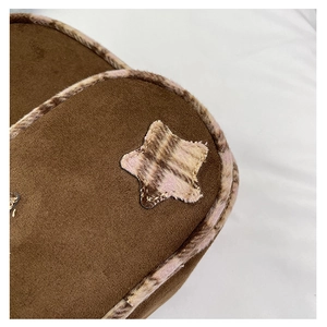Dettaglio di scarpe in scamosciato marrone con bordo in ecopelliccia a quadri e stella